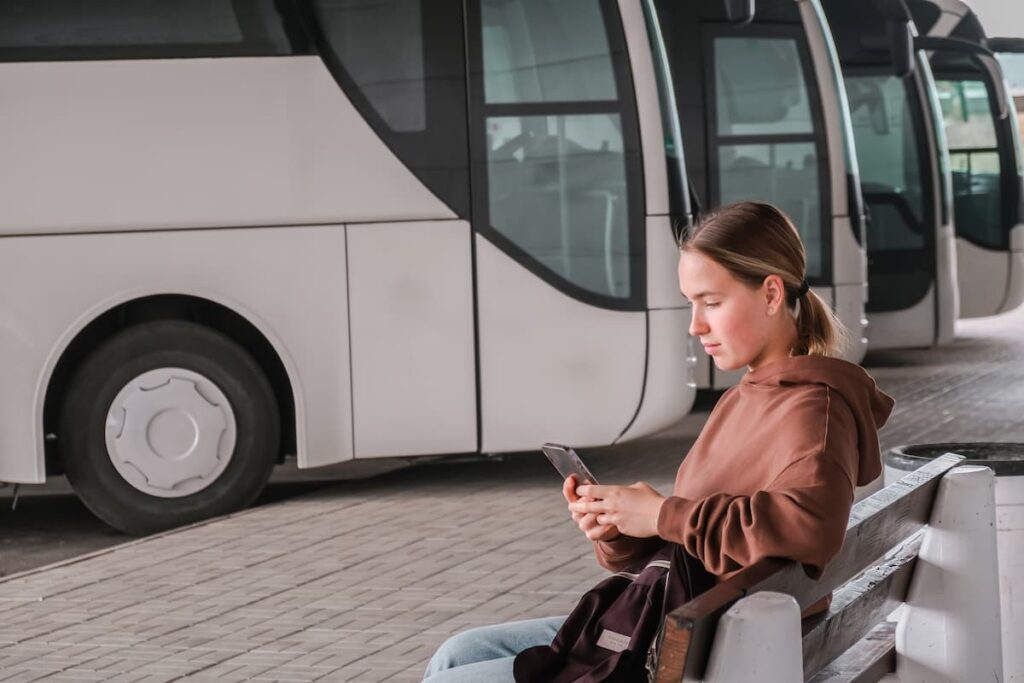 Imagem mostra jovem mulher em terminal rodoviário.