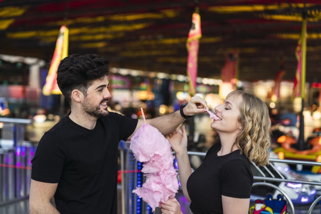 Imagem mostra casal feliz comendo algodão-doce na Expominas Belo Horizonte.