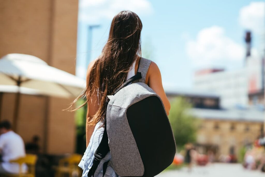 Imagem mostra mulher viajando com mochila pequena, um dos itens para levar em uma viagem para Belo Horizonte