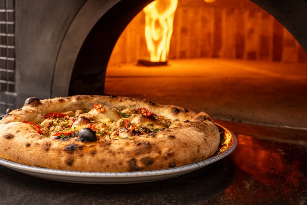 Imagem mostra pizza prepara em Forno a lenha.