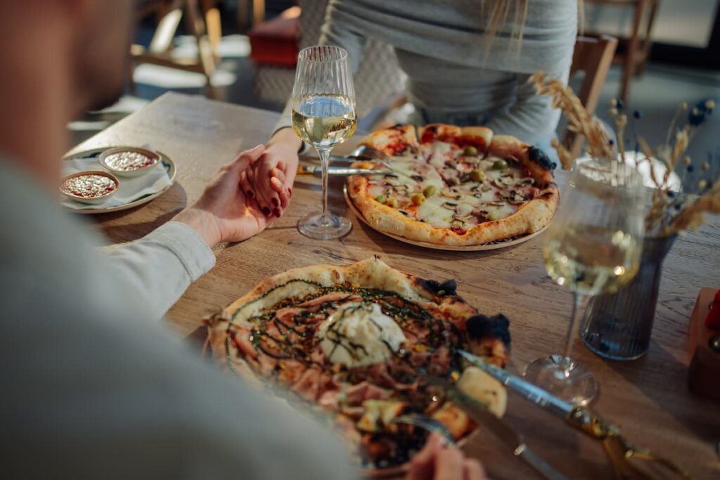 Imagem mostra pessoas saboreando deliciosas pizzas em uma das melhores pizzarias de Belo Horizonte.